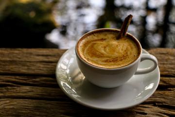 Hot cofffee cup on wooden with painting leaf