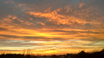 Sunset from the window. Orange clouds. City Silhouette.