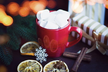 Red cup of coffee or hot chocolate with marshmallow on wooden dark background. Cinnamon sticks, stars with bokeh. Winter concept. Hot coffe with marshmallow.