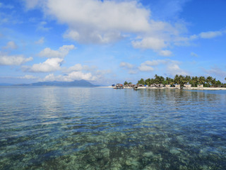 Stunning view of the ocean with coral reef, blue sky and island background.