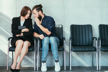 man whispering to a womans ear. office gossip and secrets. colleagues in business workspace.