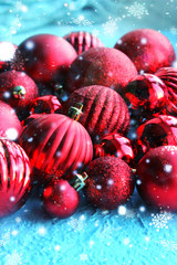 Fototapeta na wymiar Christmas card. Beautiful Christmas background. Lots of red balls big and small on blue texture background. White snowflakes circling, the effect of falling snow. Copy space.