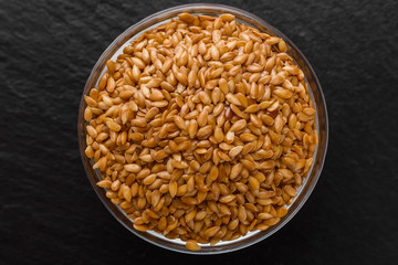 seeds of golden flax on a dark stone background