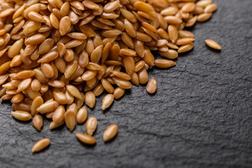 seeds of golden flax on a dark stone background