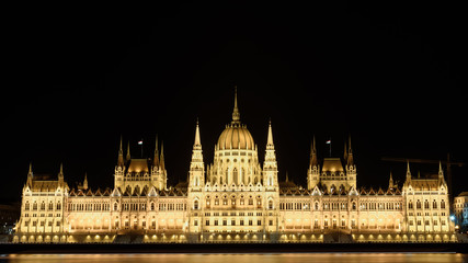 Fototapeta na wymiar Hungarian Parliament building, in Budapest, at night. The building is lit up, and the Danube is flowing smoothly in front of it.