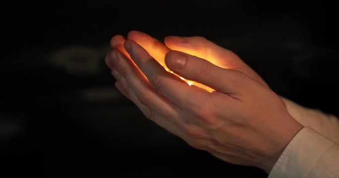 Beautiful male hands open and show a light bulb with a warm light