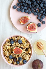Granola with fruits and honey on a white wooden table, top view. Flat lay, from above, overhead. Close-up.