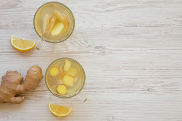 Homemade ginger tea with lemon on white wooden table, overhead view. Space for text.