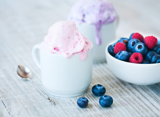 Berry ice cream in white cups and fresh berries: raspberries and blueberries