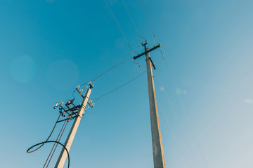 Power lines on background of blue sky close-up. Electric hub on pole. Electricity equipment with...