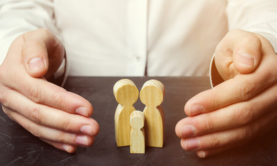Insurance agent holds hands over family. The concept of insurance of family life and property....