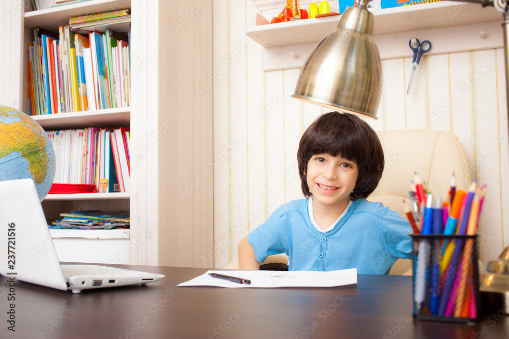 Wall mural smiling schoolboy doing homework