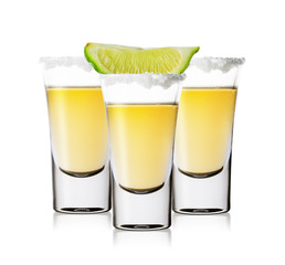 Three glasses of golden tequila with salt and lime