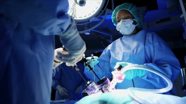 Medical Laparoscopic Operation carried out by Caucasian male and female specialist team in scrubs and African American Anesthesiologist 