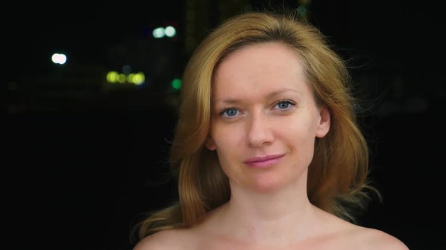 portrait of a young woman without make-up with bare shoulders against the blurry lights of the city. copy space