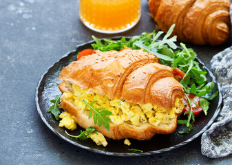 Breakfast of croissant with scrambled eggs and salad.