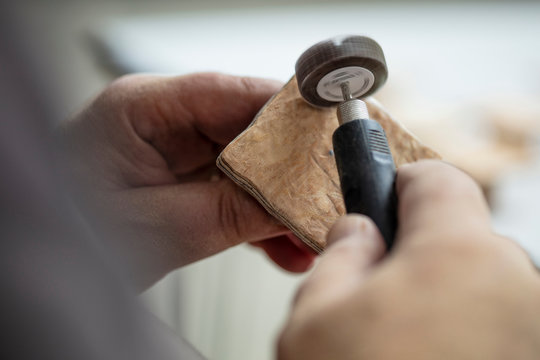 Carpenter sanding wood square with sanding tool