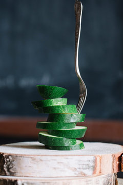 Stacked sliced courgettes and fork on rustic cutting board