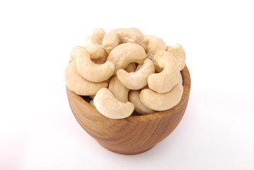 Raw cashews in a wooden bowl on a white background.