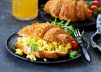 Breakfast of croissant with scrambled eggs and salad.