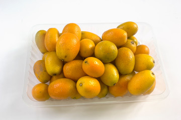 Fresh juicy Fortunella in a clear plastic box. On white backdrop