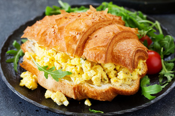 Breakfast of croissant with scrambled eggs and salad.