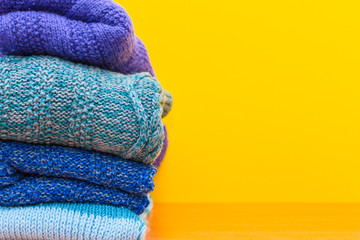 stack of knitted clothes on yellow background