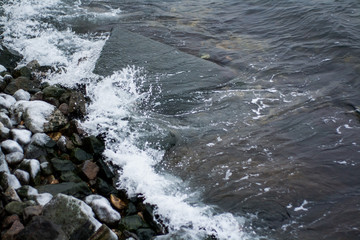 Sea waves break on frozen stones