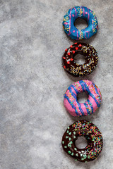 homemade doughnuts with colored frosting and different sprinkles on a gray background