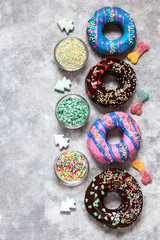 homemade doughnuts with colored frosting and different sprinkles on a gray background