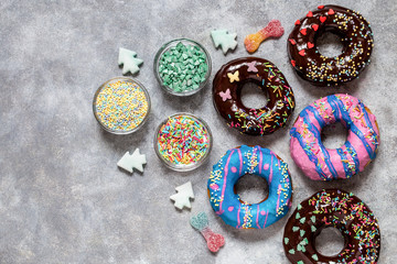 homemade doughnuts with colored frosting and different sprinkles on a gray background
