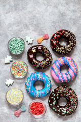 homemade doughnuts with colored frosting and different sprinkles on a gray background