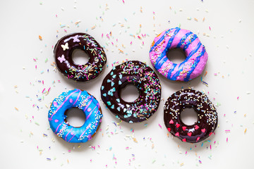 homemade doughnuts with colored frosting and different sprinkles on white background
