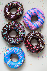 homemade doughnuts with colored frosting and different sprinkles on white background
