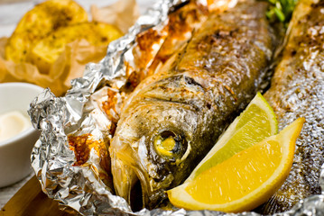 Fresh baked fish sea bass (Dicentrarchus labrax) on a light wooden background