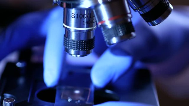 Scientist hands with microscope close-up shot in the laboratory. Medical laboratory research tools in the hands in gloves. Close up. Forensic examination. 4K UHD..