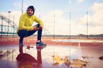 Portrait of young athlete man in windbreaker preparing to exercise outdoors
