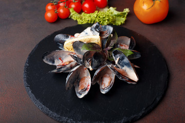 Seafood mussels in cream sauce with lemon and basil on a stone and rusty background