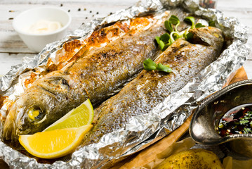 Fresh baked fish sea bass (Dicentrarchus labrax) on a light wooden background