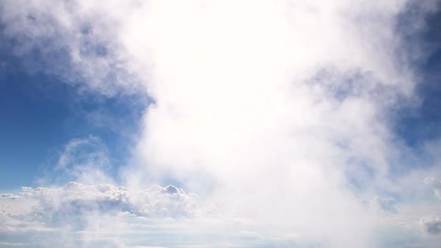 White flufly clouds passing blue sky with bright sun shining