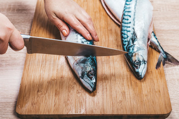 cook cuts raw mackerel fish