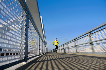 Attractive fit man running fast along big modern bridge. Exercising, Jogging, Sport, Winter. Male athlete running.