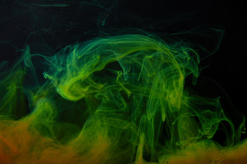 Obraz premium black background with abstract green and orange swirls of paint