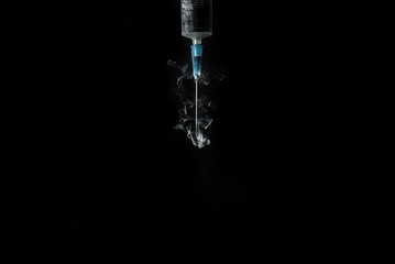 syringe with smoke or paint swirls isolated on black