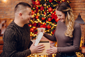husband gives his wife christmas present at home
