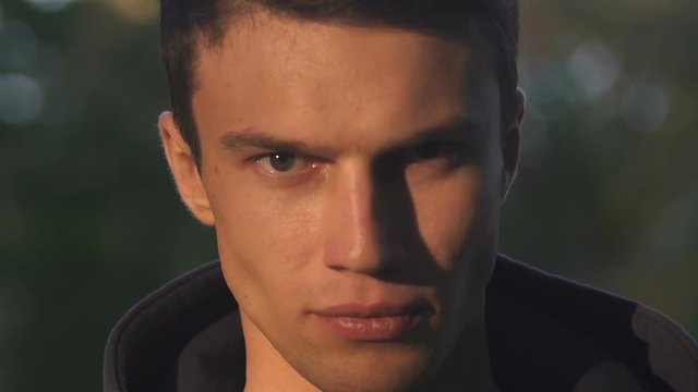 Young man aggressively looking at camera, hate, revenge desire, face close-up