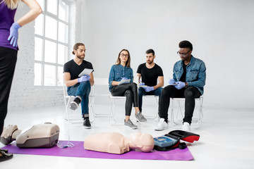 Fototapeta premium Group of young people sitting during the first aid training in the white classroom