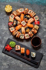 sushi rolls Asian food on a round slate black Board with wasabi and ginger, soy sauce