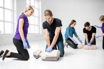Group of young people practising to make artificial breathing with medical dummies during the first...