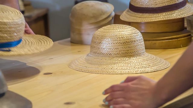 A man is putting a really nice straw hat on the table in front of a customer.